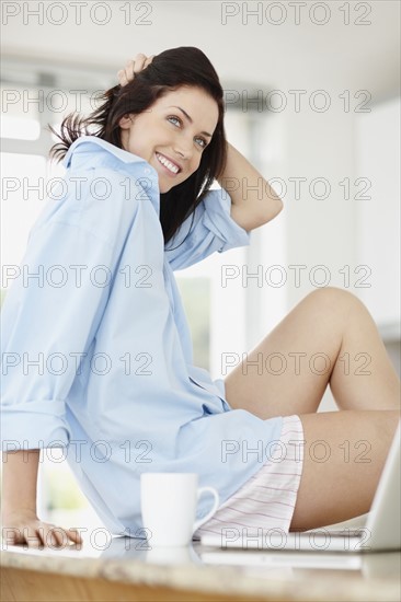 Beautiful brunette sitting on kitchen counter. Photo. momentimages