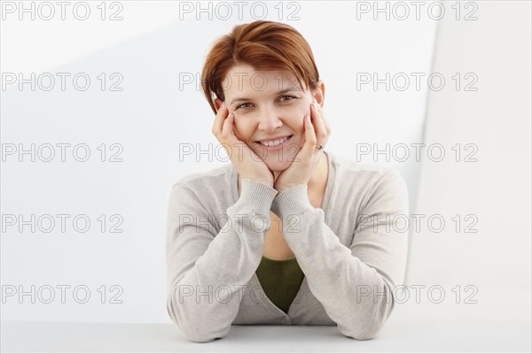 Charming woman sitting at table. Photo : momentimages