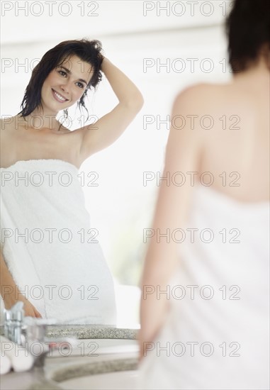 Woman looking at her reflection in mirror. Photo : momentimages