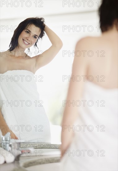 Woman looking at her reflection in mirror. Photo. momentimages