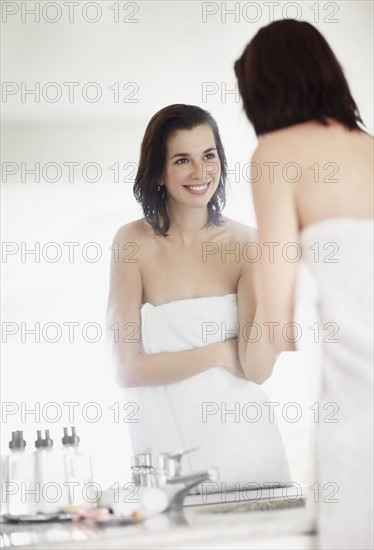 Woman looking at her reflection in mirror. Photo : momentimages