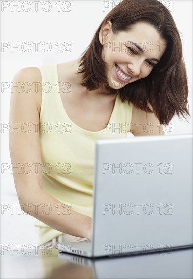 Smiling brunette woman browsing the internet. Photo : momentimages