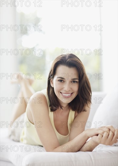Cheerful brunette woman relaxing on couch. Photo : momentimages
