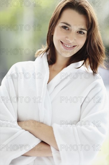 Smiling brunette woman wearing a bathrobe. Photo : momentimages