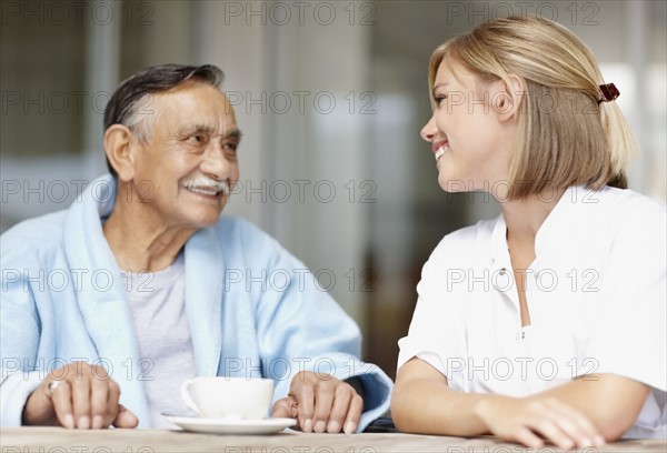 Nurse and senior patient sitting at table. Photo. momentimages