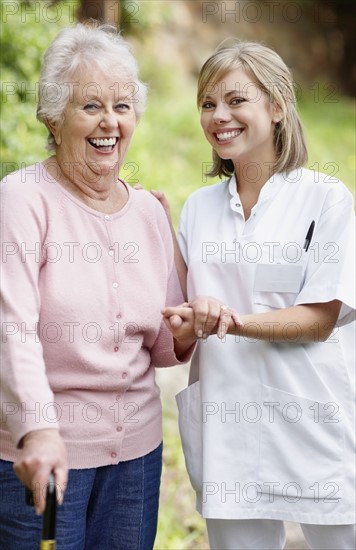 Nurse assisting senior walking with a cane. Photo : momentimages