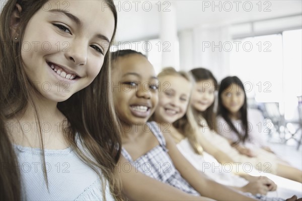 Group of young girls sitting in a row. Photo. momentimages