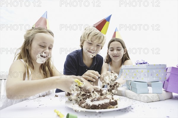 Children eating birthday cake with their hands. Photo. momentimages