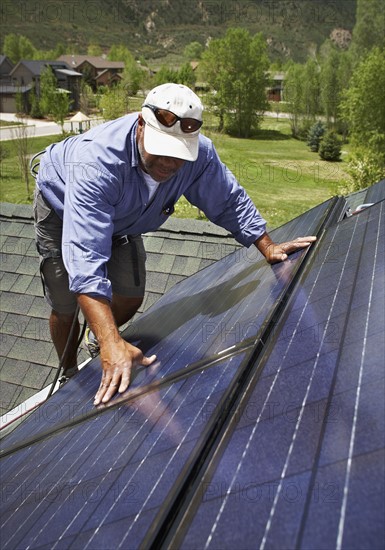 Construction worker installing solar panel on roof. Photo : Shawn O'Connor