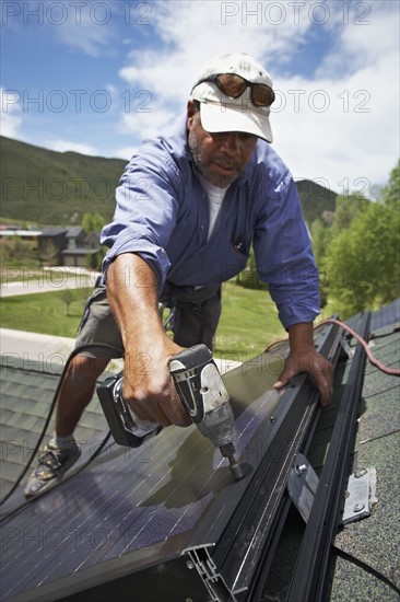 Construction worker installing solar panel on roof. Photo. Shawn O'Connor