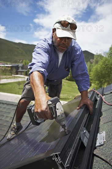 Construction worker installing solar panel on roof. Photo : Shawn O'Connor