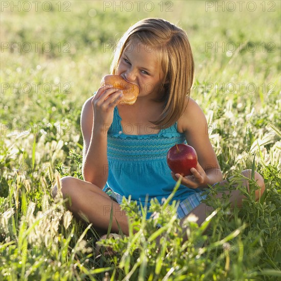 Young girl eating a doughnut. Photo : Mike Kemp