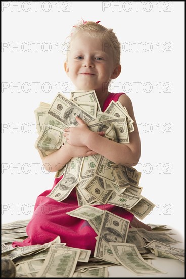 Young girl holding a pile of money. Photo. Mike Kemp
