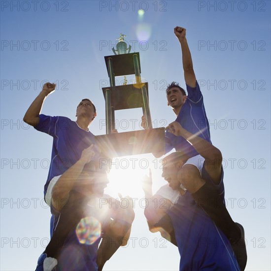 Football players holding trophy. Photo : Mike Kemp