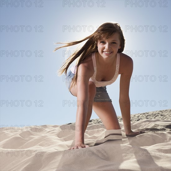 Pretty woman kneeling in sand. Photo. Mike Kemp