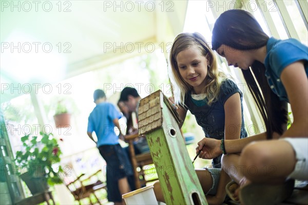 Two girls painting a birdhouse. Photo : Tim Pannell