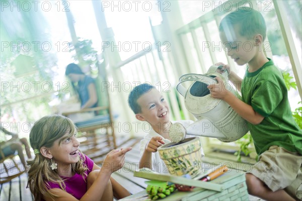 Young children watering seeds in a planter. Photo : Tim Pannell