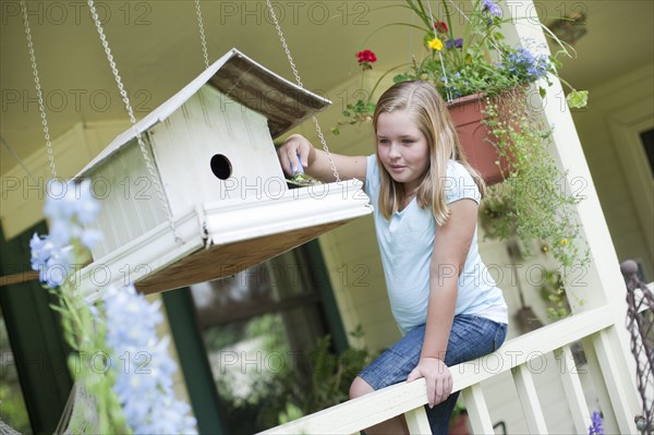 Young girl putting seeds in birdhouse. Photo : Tim Pannell