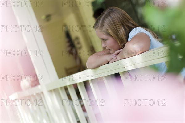 Young girl gazing over porch railing. Photo : Tim Pannell