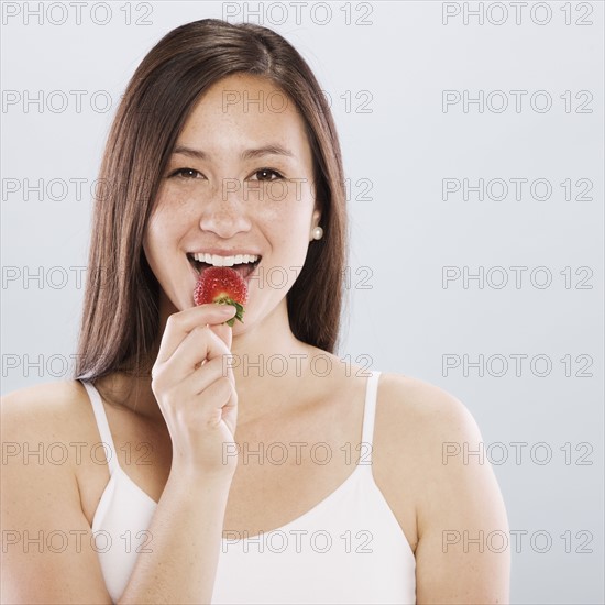 Brunette woman eating a strawberry. Photo : FBP