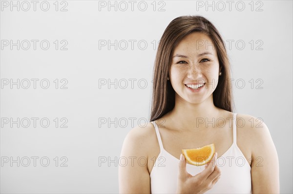 Woman holding a slice of orange. Photo : FBP