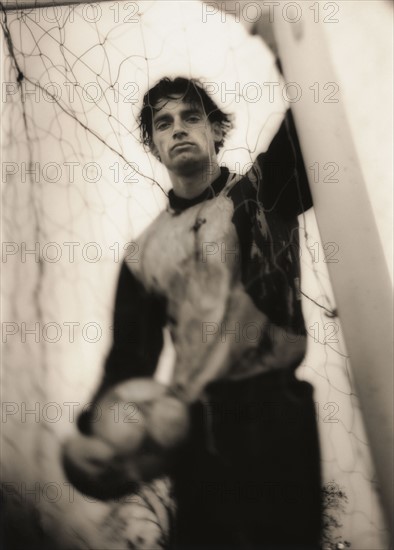 Soccer player standing behind net. Photo. FBP