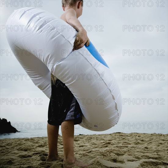 Young boy standing in an inflatable tube at the beach. Photo : FBP
