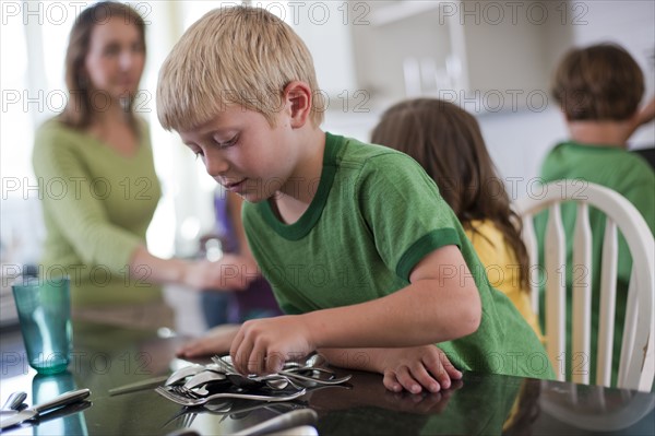 Young boy setting the table. Photo : Tim Pannell