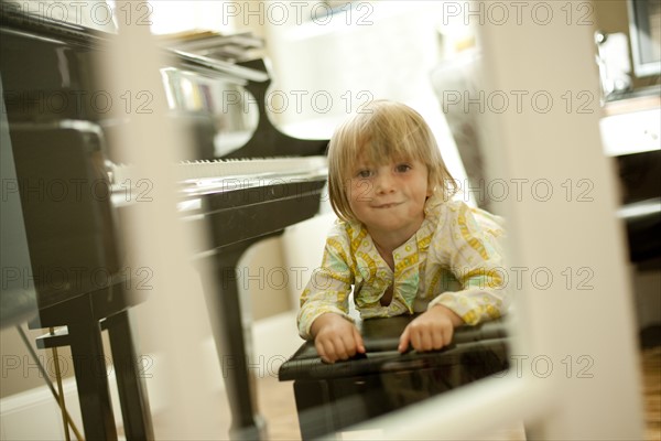 Young girl lying on piano bench. Photo. Tim Pannell