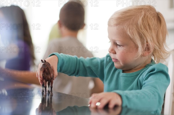 Young girl playing with toy horse. Photo : Tim Pannell