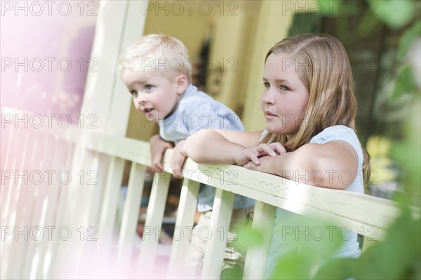 Brother and sister gazing over porch railing. Photo. Tim Pannell