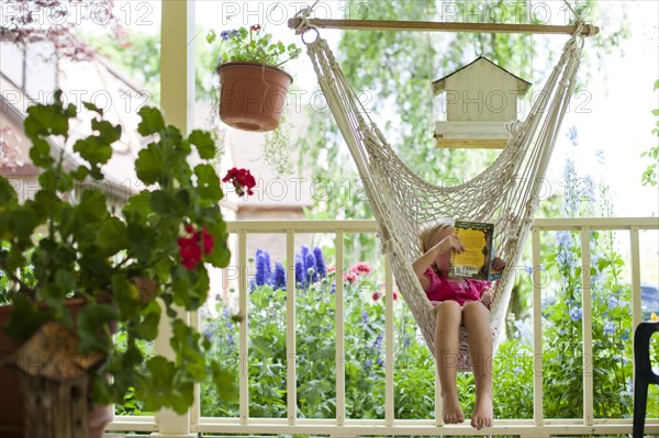 Young girl reading in hammock. Photo : Tim Pannell