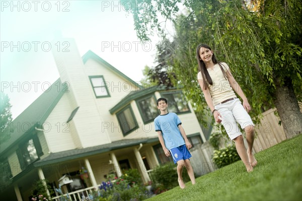 Brother and sister walking on lawn. Photo : Tim Pannell
