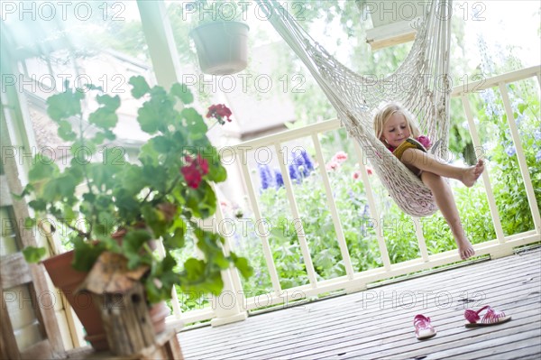 Young girl reading in hammock. Photo : Tim Pannell