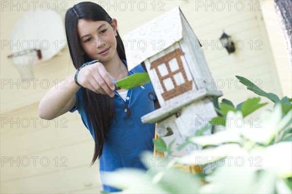 Young girl putting bird seed in birdhouse. Photo : Tim Pannell