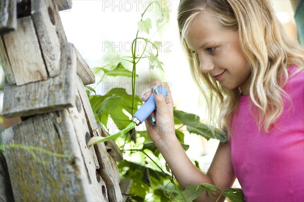 Young girl putting bird seed in birdhouse. Photo : Tim Pannell