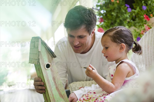 Father helping his daughter paint a birdhouse. Photo : Tim Pannell