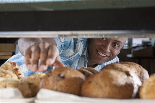 Man reaching for muffin in bakery. Photo : Dan Bannister