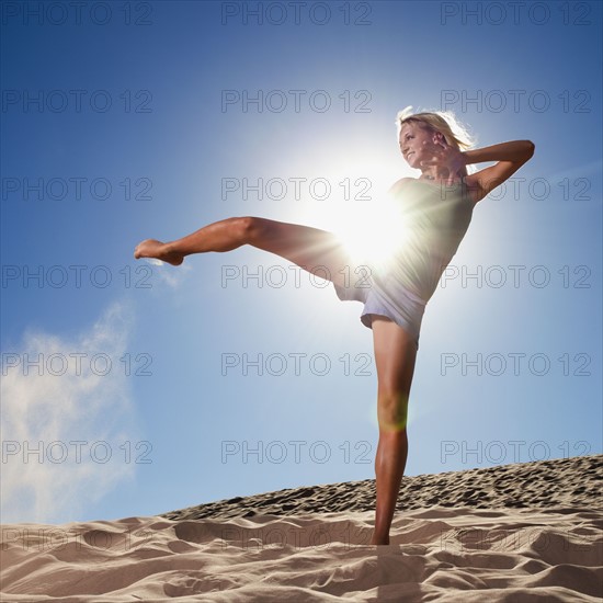 Female dancer kicking her leg on the beach. Photo : Mike Kemp