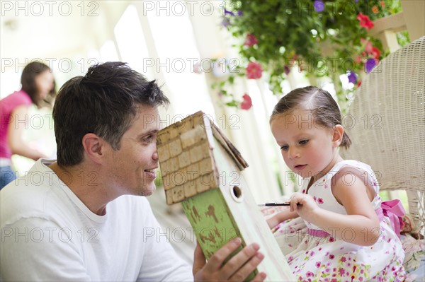 Father helping his daughter paint a birdhouse. Photo : Tim Pannell