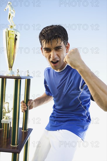 Football player holding trophy. Photo : Mike Kemp