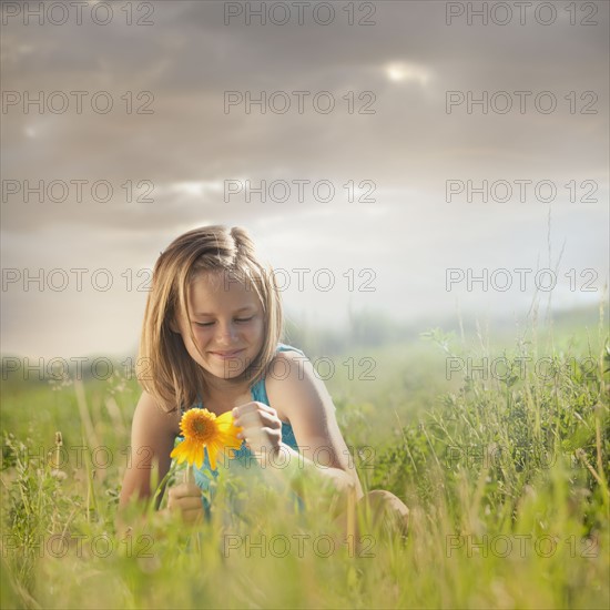 Young girl pulling petals off of gerbera daisy. Photo. Mike Kemp