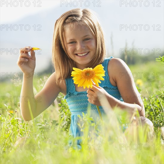 Young girl pulling petals off of gerbera daisy. Photo. Mike Kemp