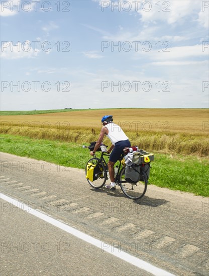 Adventure cyclist biking on rural road. Photo : John Kelly