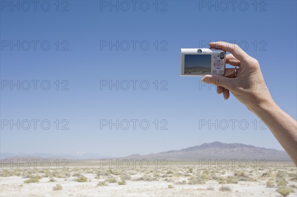 Hand holding a camera in the desert. Photo : Chris Hackett