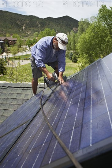 Construction worker installing solar panel on roof. Photo. Shawn O'Connor