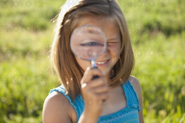 Young girl holding a magnifying glass. Photo : Mike Kemp