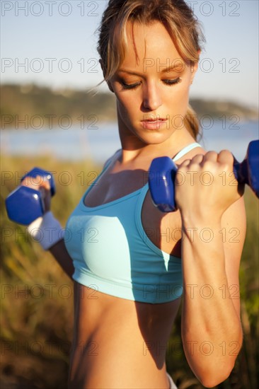 Woman lifting weights outdoors. Photo : Take A Pix Media