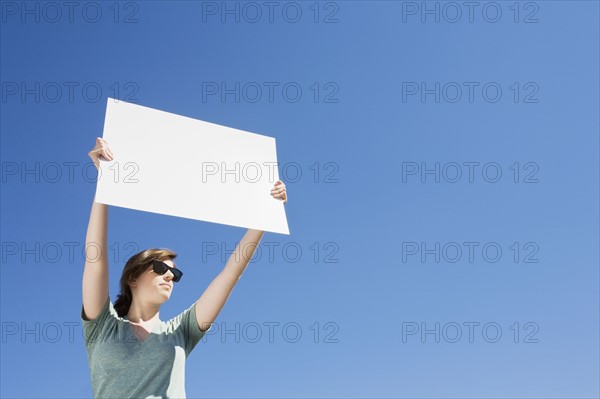 Young woman holding a blank placard. Photo : Chris Hackett
