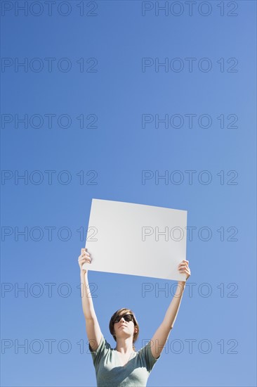Young woman holding a blank placard. Photo : Chris Hackett